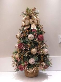 a small christmas tree with ornaments and bows on it's top, in a basket