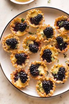 blackberries and cream pies on a white plate with green garnishes