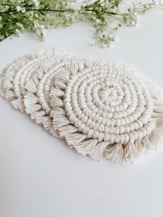 three pieces of white crochet are laying on a table next to some flowers