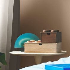 a wooden box sitting on top of a white table next to a blue vase and lamp