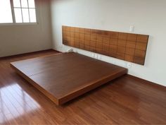 an empty room with hard wood floors and a wooden bed frame on the wall above it