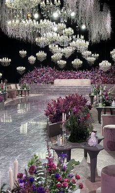 a room filled with lots of purple flowers and chandeliers hanging from the ceiling