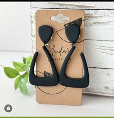 pair of black earrings on card next to plant