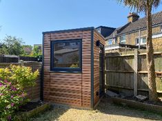 a small wooden shed sitting in the middle of a yard next to a palm tree