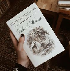 a person holding up a book in their hand with the title black house written on it