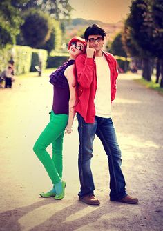 a man and woman standing on the side of a road with trees in the background