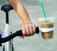 a person riding a bike with a cup on it's handlebar and the caption says bicycle coffee cup holder