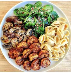 a white plate topped with pasta, meat and veggies on top of a wooden table