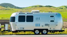 an rv is parked on the side of the road in front of a green field