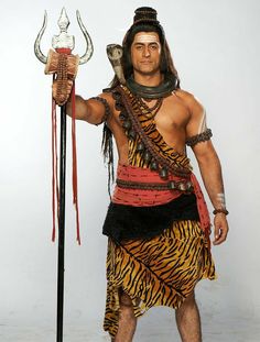 a man dressed up as a native american warrior holding a spear and an animal skin costume