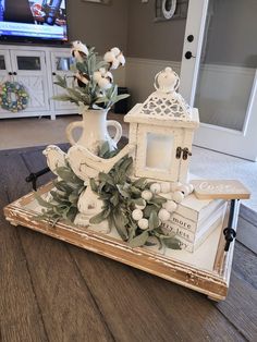 a white vase with flowers on top of a wooden tray