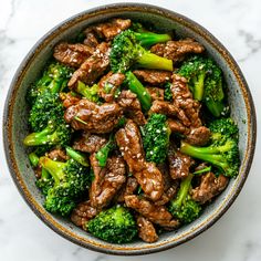 beef and broccoli in a bowl on a marble counter top, ready to be eaten