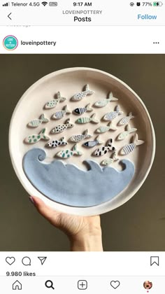 someone is holding up a ceramic plate with fish on it