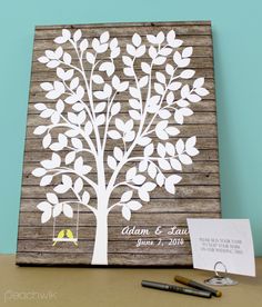 a wedding guest book with a tree cut out on it and a bird perched on the branch