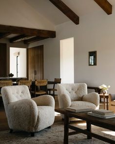 a living room filled with furniture next to a wooden table and ceiling mounted light fixture