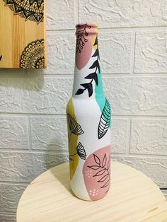 a painted vase sitting on top of a wooden table next to a brick wall and painting