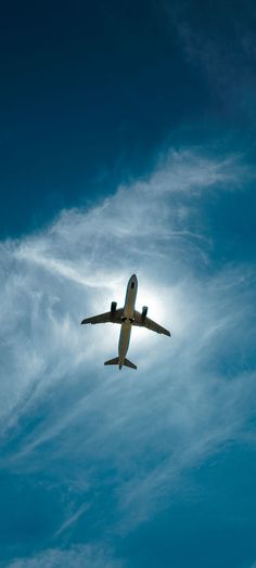 an airplane is flying through the blue sky with white clouds in the backround