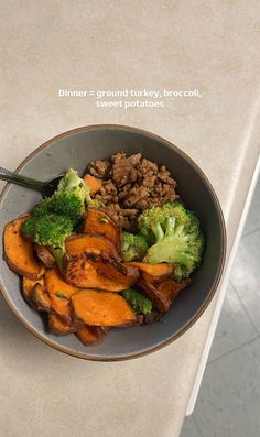 a bowl filled with meat and broccoli on top of a white countertop