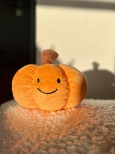 an orange stuffed animal sitting on top of a table next to a shadow cast wall