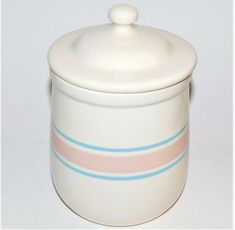 a white ceramic container with blue and pink stripes on the bottom, sitting on a white surface