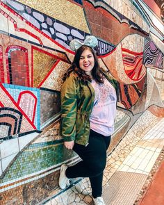 a woman standing in front of a colorful wall