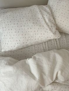 an unmade bed with white sheets and pillows