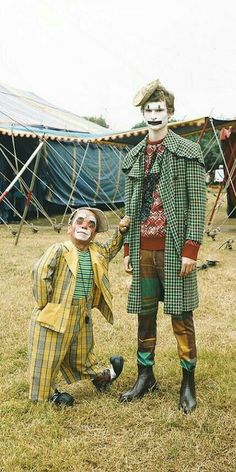 two clowns standing next to each other in front of tents and tented area