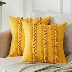 four yellow pillows on a bed with white sheets