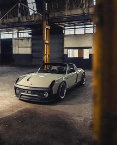 a car parked in an old warehouse with no doors on the door and it's hood up