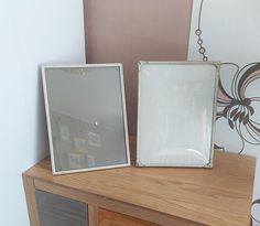 two framed pictures sitting on top of a wooden dresser