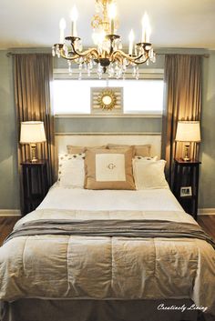 a bedroom with a bed, chandelier and two lamps