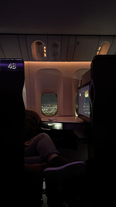 the interior of an airplane that is lit up at night with lights on and there are two people sleeping