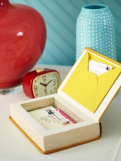 an open box sitting on top of a table next to a red vase and clock