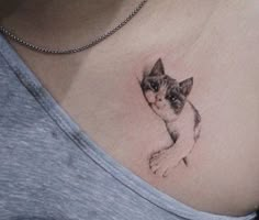 a woman's chest with a cat tattoo on the top and bottom part of her stomach