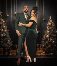 a man and woman standing next to each other in front of a christmas tree