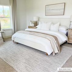 a large white bed sitting in a bedroom on top of a wooden dresser next to a window