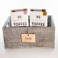 small wooden box with tags on each side and two toffee packets in it