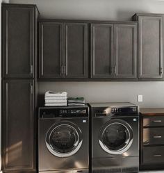 a washer and dryer in a laundry room with cabinets on the wall behind them