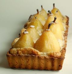 pear tart with powdered sugar topping on white table top, ready to be eaten