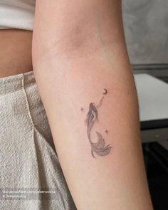 a woman's arm with a small fish tattoo on the left side of her arm