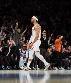 the basketball player is walking on the court with his hands in the air as he celebrates