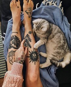 two people with tattoos on their legs and one has a cat laying next to them