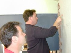 two men working on a wall in a room