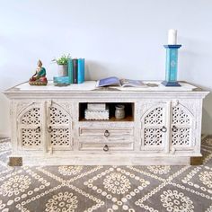 a white wooden table with books and vases on top