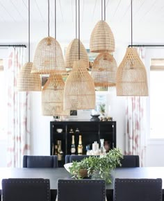 a dining room table and chairs with hanging lights above it in front of a window