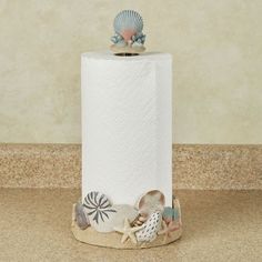 a roll of toilet paper sitting on top of a counter next to seashells