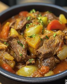 a close up of a bowl of food with meat and vegetables in it on a table