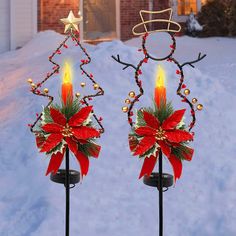 two christmas decorations on top of metal poles in the snow