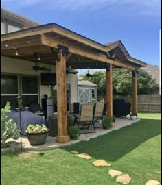 an outdoor covered patio with chairs and tables on the grass in front of a house