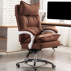 a brown recliner chair sitting in front of a computer desk with a monitor on it